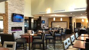 Een hotel lobby met verschillende zithoeken, een open haard, een televisiescherm en een receptiebalie.