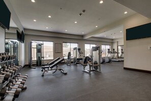 A gym with treadmills, dumbbells, and weight machines.