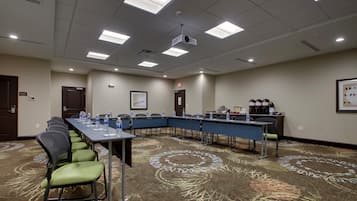 A conference room with a long table, chairs, water bottles, a projector, and a coffee station.