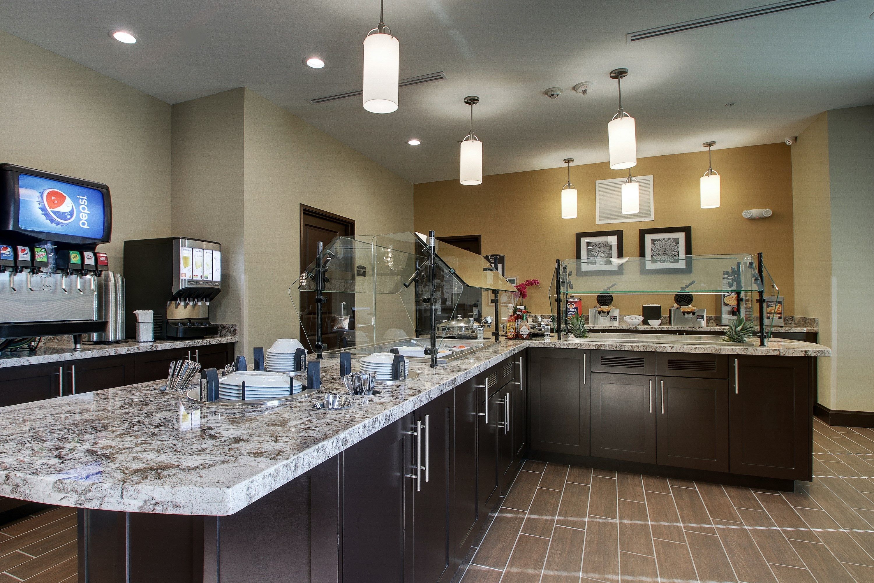 A modern kitchen with a granite countertop, dark cabinets, and a built-in refrigerator.