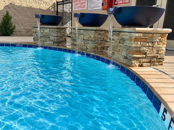 Ein Swimmingpool mit einer Steinmauer und zwei großen Schalen darauf.
