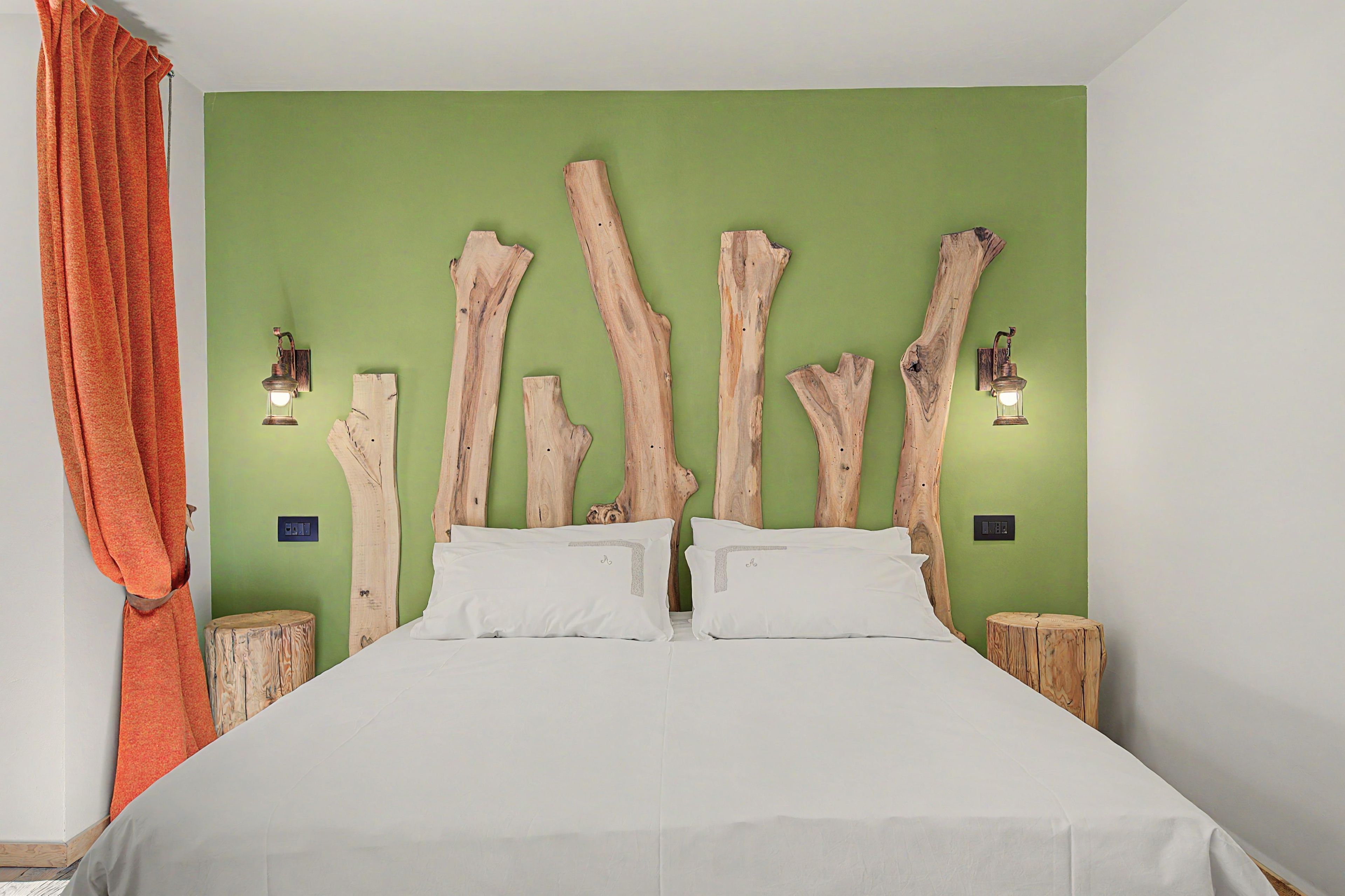 Een slaapkamer met een bed, groene wanden en een houten hoofdeinde.