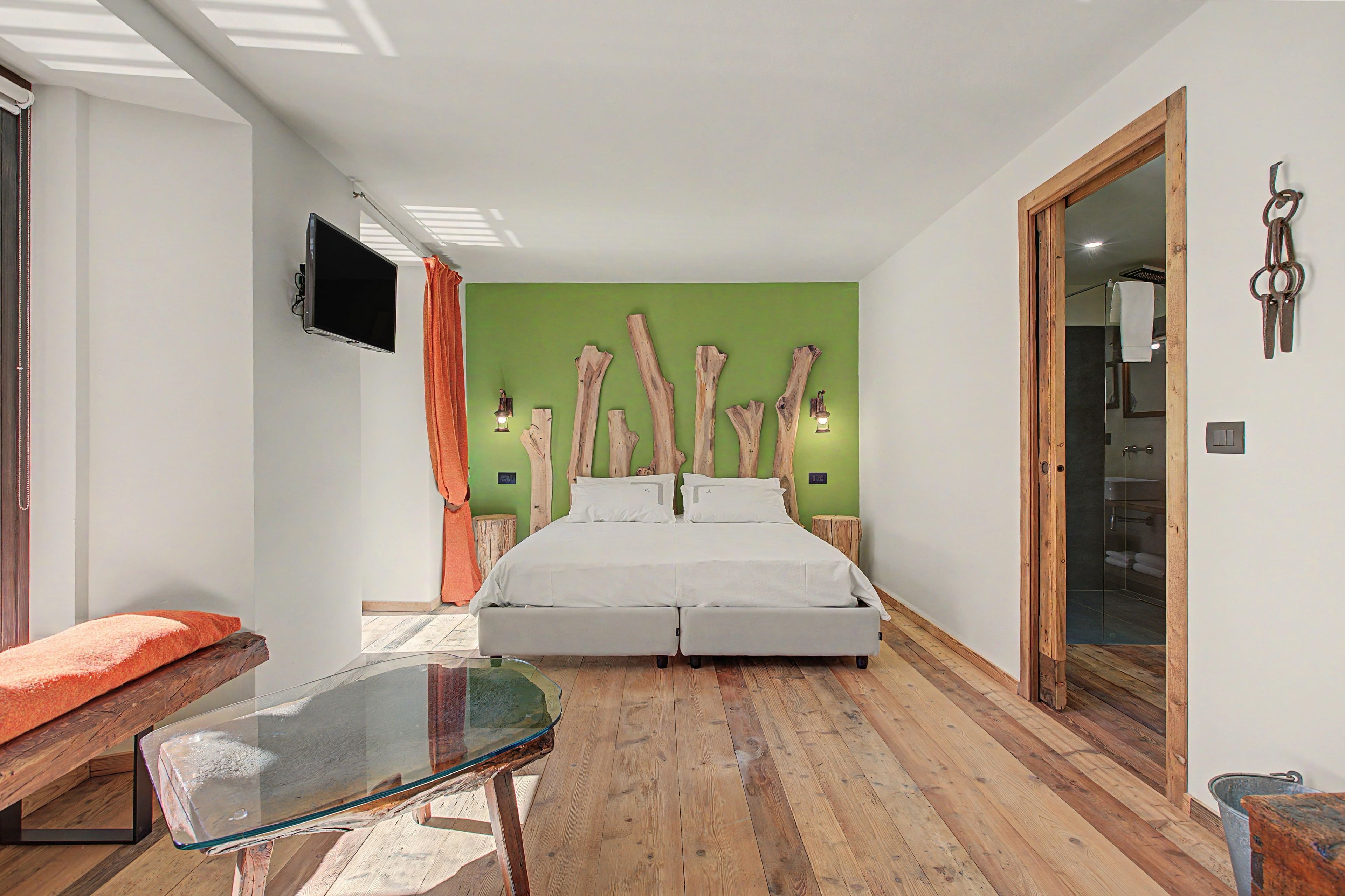 Une chambre à coucher moderne avec un lit, une table en verre et un mur d’accent de couleur verte.
