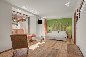 Une chambre à coucher moderne avec un lit, une chaise, une petite table et un téléviseur.