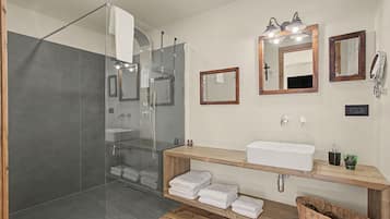 Ein modernes Badezimmer mit einer in Glas abgeschlossenen Dusche, einem Holzbadezimmer-Möbelstück mit Waschbecken und zwei Spiegeln.