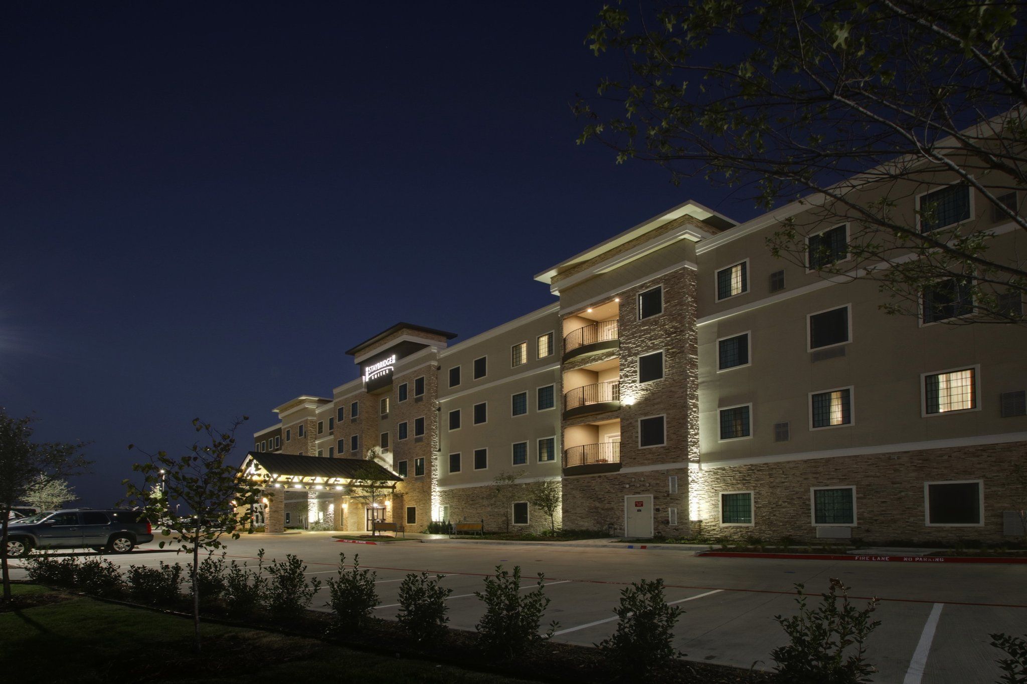 A multi-story hotel with a stone facade, multiple balconies, and a well-lit entrance.