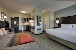 Ein Hotelzimmer mit Bett, Sofa, Schreibtisch und einer Küchenzeile.