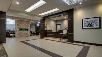 A spacious lobby with a reception desk, seating area, and a stone fireplace.