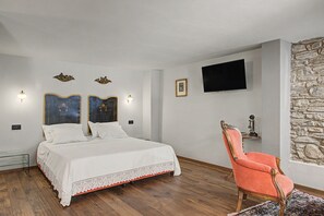 A bedroom with a bed, a chair, a television, and decorative wall elements.