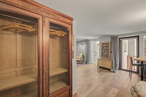 A room with a wooden wardrobe, a dining table, and a chair.