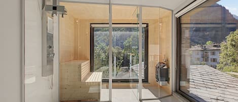 Un interno moderno con una porta in vetro che dà su un balcone con vista su una zona boschiva.