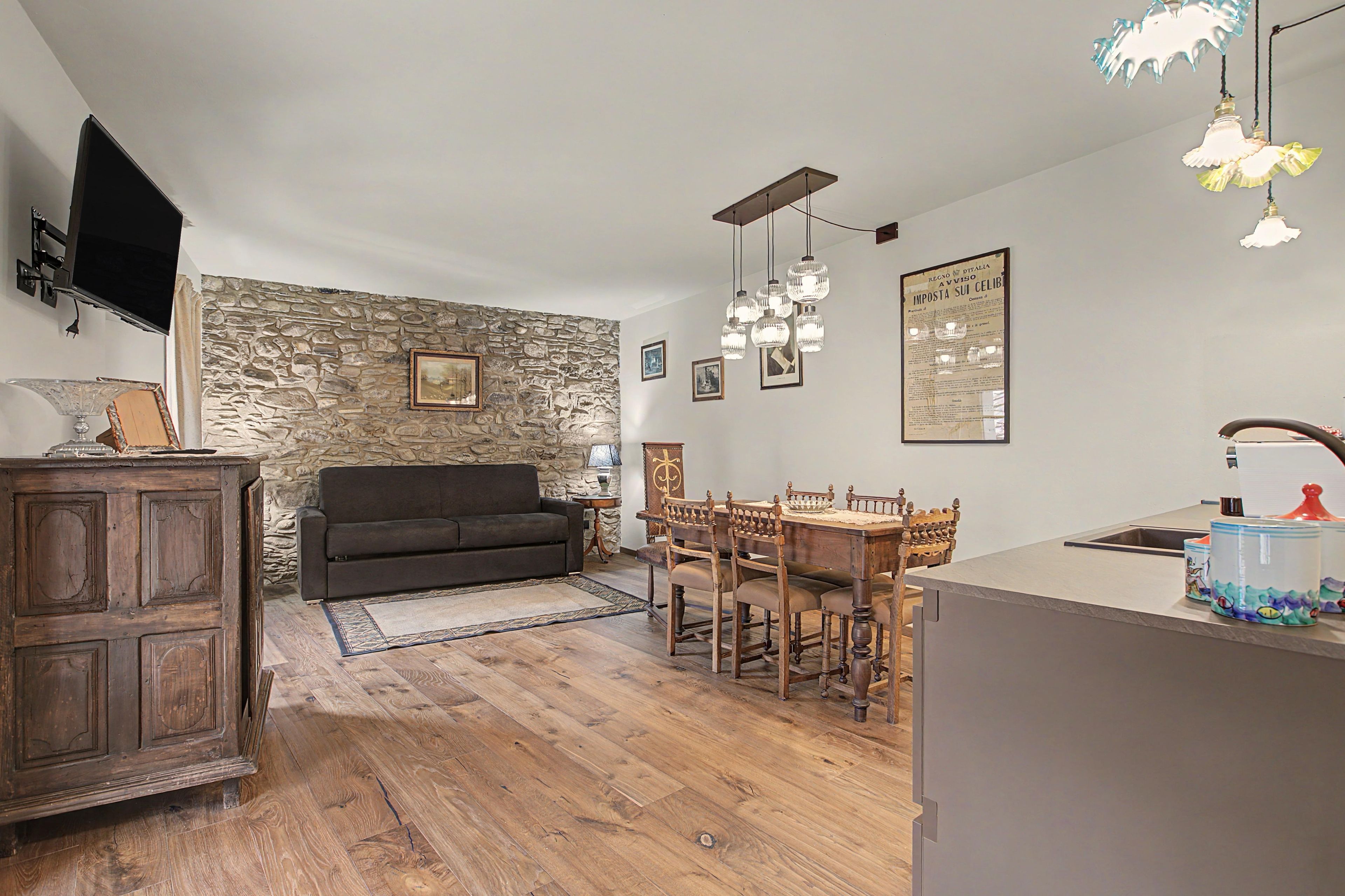 Eine moderne Küche mit Steinwand, Esstisch aus Holz und einem an der Wand befestigten Flachbildfernseher.