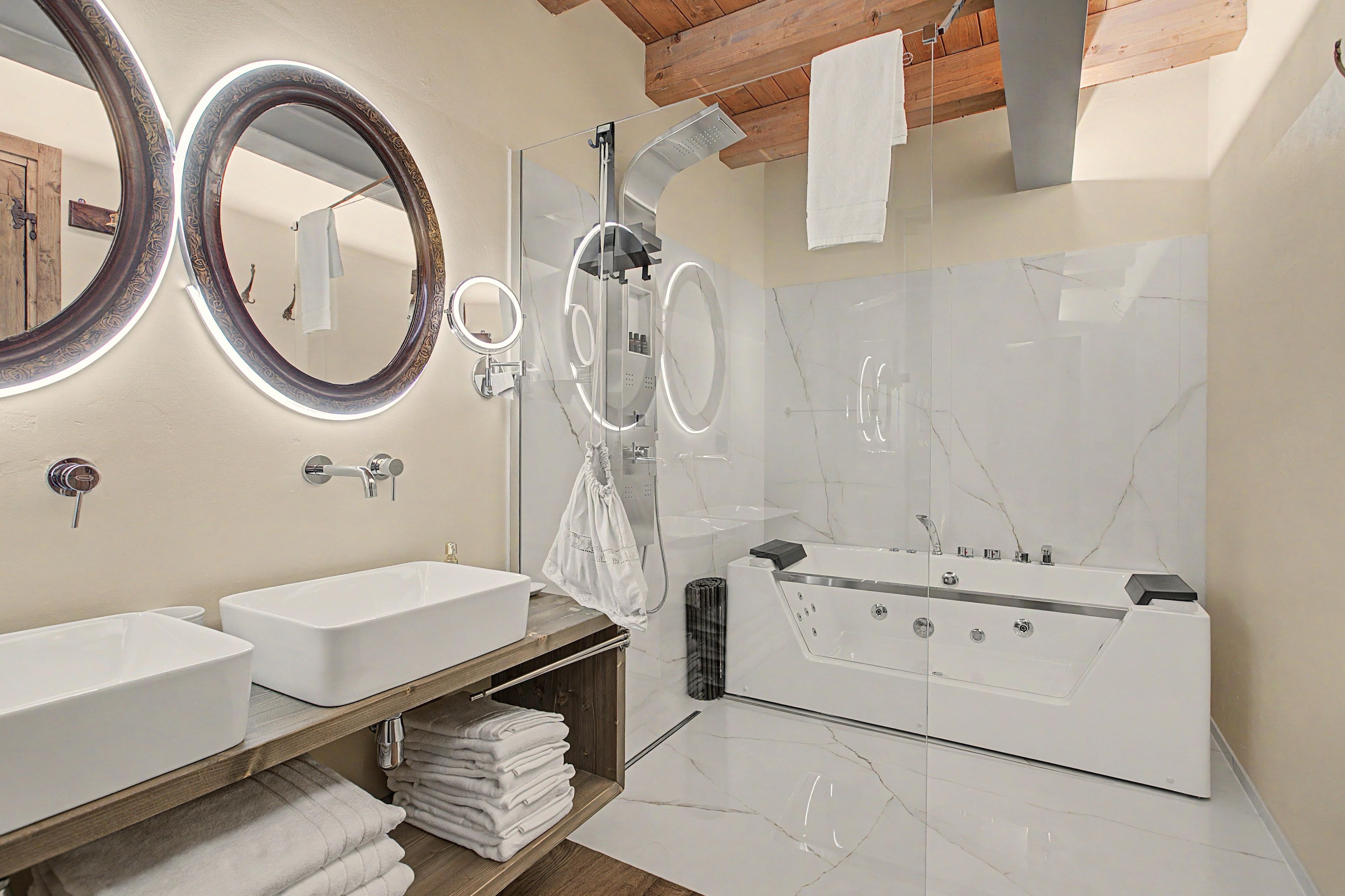Ein modernes Badezimmer mit zwei Waschbecken, einem großen Spiegel, einer Badewanne und einem Handtuchhalter.
