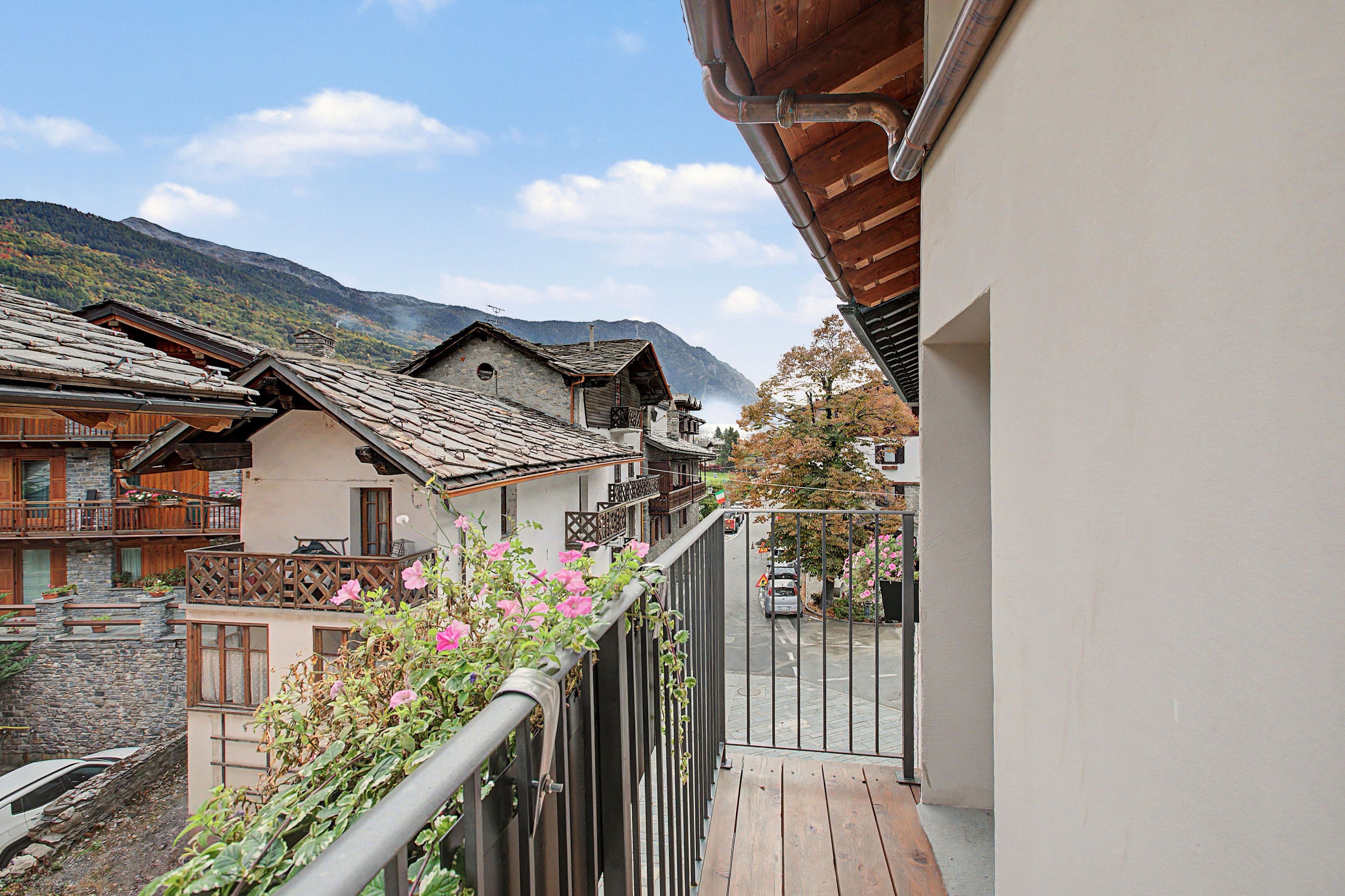 Un balcon offrant une vue sur des bâtiments traditionnels et une montagne en arrière-plan.