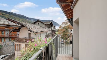 Een balkon met uitzicht op traditionele gebouwen en een berg op de achtergrond.