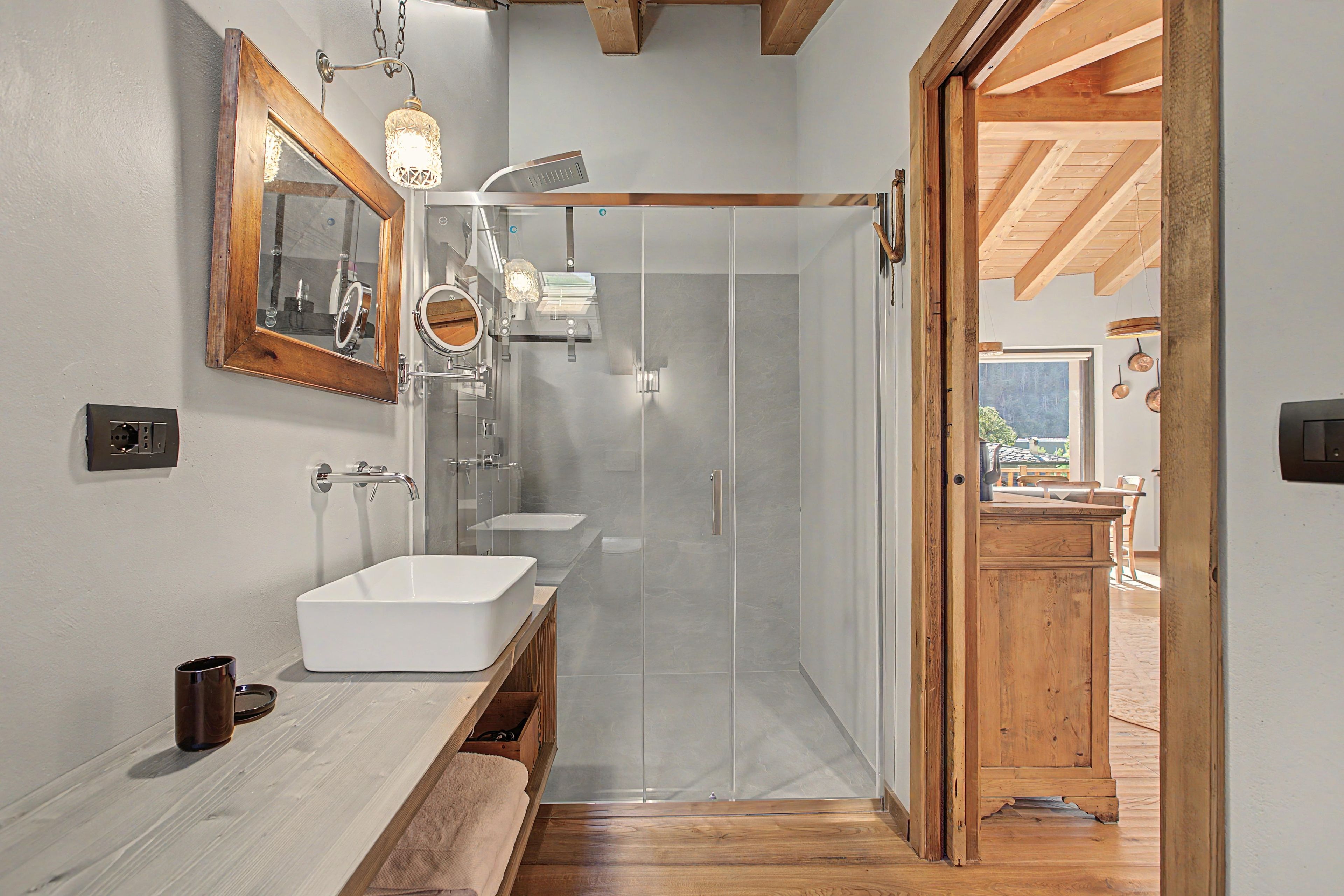 A modern bathroom with a large mirror, three sinks, and a walk-in shower.