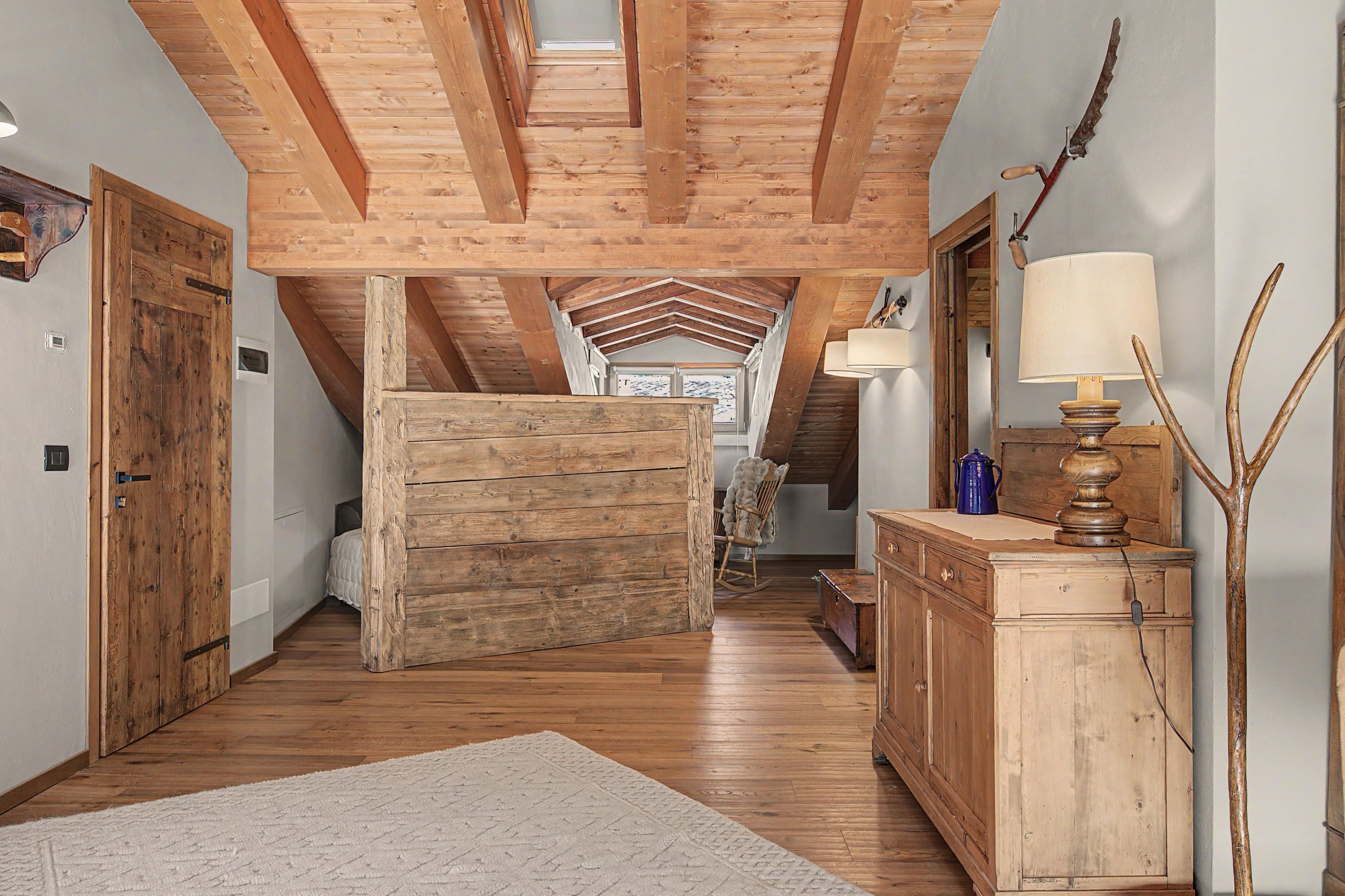 Un intérieur en bois avec un plafond haut, un fauteuil à bascule et une lampe.