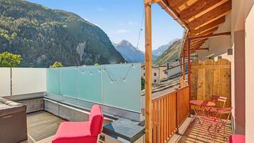 Une terrasse avec vue sur les montagnes, une pergola en bois et des chaises rouges.
