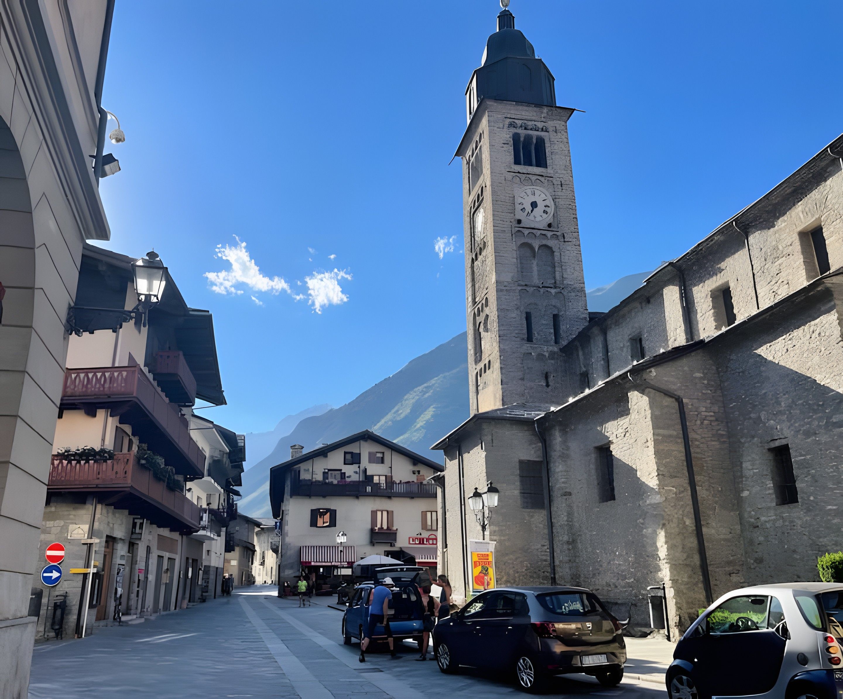 Una calle con edificios, una torre del reloj y una montaña al fondo.
