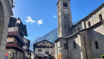 Una calle con edificios, una torre del reloj y una montaña al fondo.