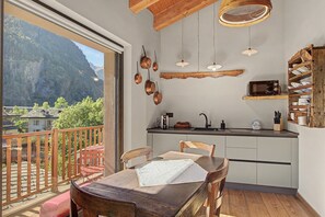 Un balcon avec une balustrade en bois, une table avec des chaises et une vue sur un paysage montagneux.