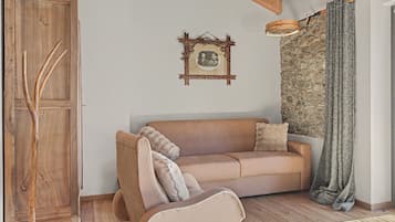 Una habitación acogedora con un armario de madera, un sofá marrón con cojines, una pared de piedra y una lámpara colgante.
