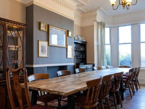 A dining room with a long wooden table and chairs, framed pictures on the wall, and a bookshelf. - Ryburn Lodge (Bridlington)