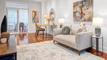 A modern living room with a sofa, a coffee table, a lamp, and a painting on the wall.