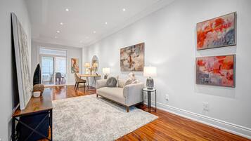 A modern living room with hardwood flooring, a grey sofa, a coffee table, and abstract wall art.