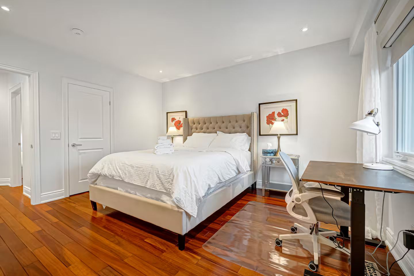 Une chambre à coucher avec un lit, des tables de chevet, un bureau et une chaise.