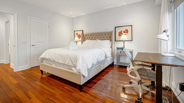 Un dormitorio con cama, mesitas de noche, un escritorio y una silla.
