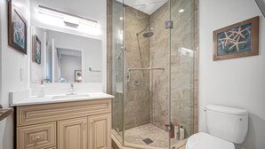 Un baño moderno con ducha envuelta en vidrio, inodoro blanco y tocador con espejo.