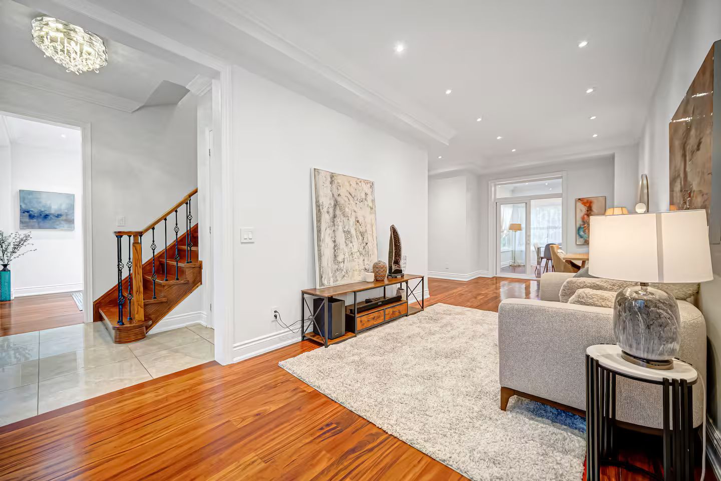 Un salon spacieux doté d’un parquet, d’un escalier et d’une grande fenêtre.