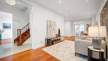 Un salon spacieux doté d’un parquet, d’un escalier et d’une grande fenêtre.