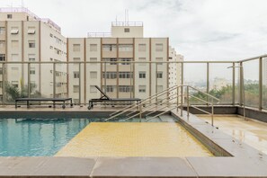 A rooftop swimming pool with a view of a residential building in the background. - E-side By Bhomy (São Paulo)
