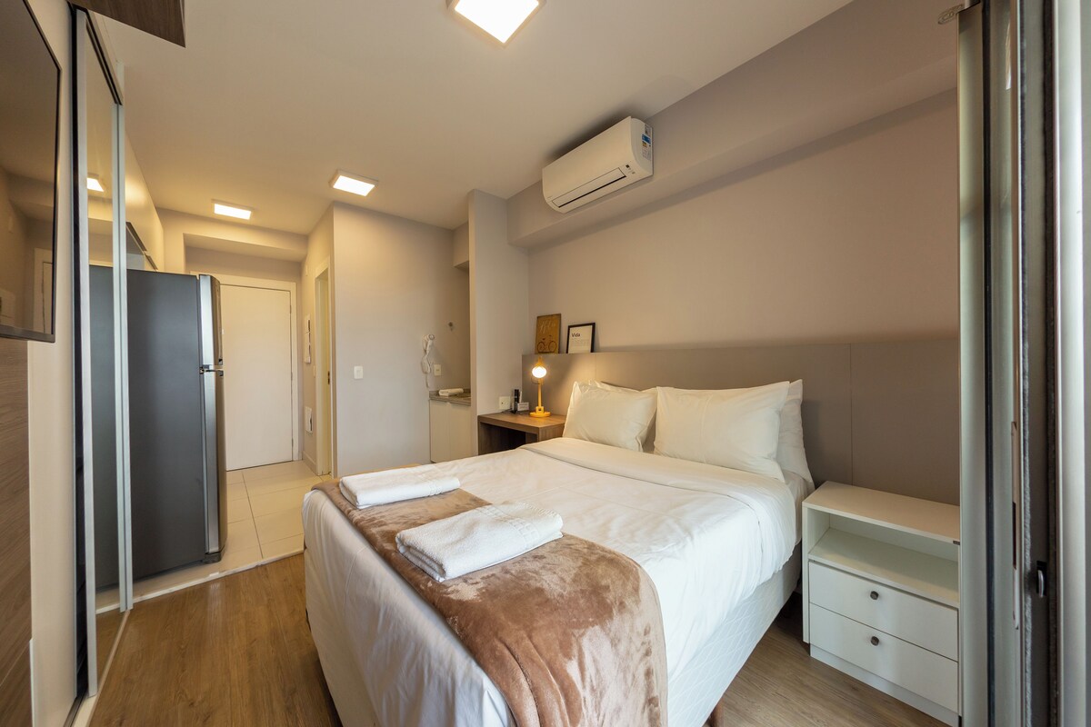 A hotel room with a bed, bedside table, and a wardrobe.