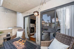 An outdoor seating area with a fire feature, wicker furniture, and a view into a living space.
