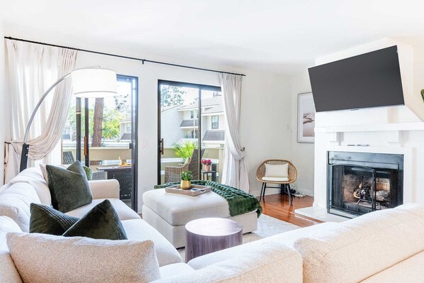 A modern living room with a sofa, a fireplace, and a large window.