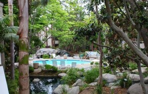 A pool area with a small waterfall, surrounded by rocks and greenery.