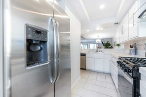 Une cuisine moderne équipée d’appareils électroménagers en acier inoxydable, d’un distributeur d’eau intégré et d’une cuisinière à gaz.