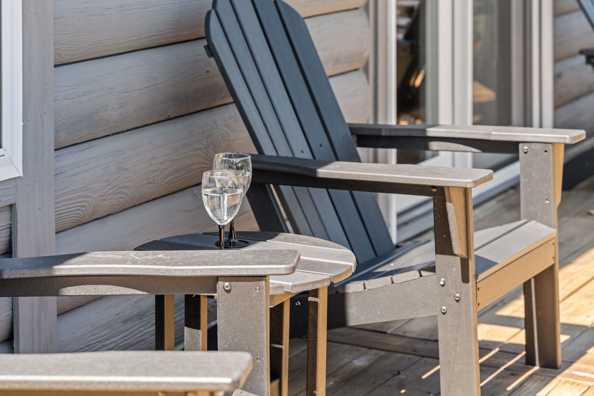 Outdoor seating with a table and chairs, a glass of water, and a wooden deck.