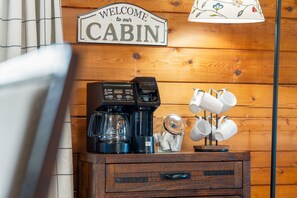 A wooden cabin interior with a coffee maker, mugs, and a welcome sign. - Gee’s Getaway is a cozy mountain retreat nestled in a peaceful setting just minutes from Boone. Relax by the fire, unwind in nature, and enjoy easy access to hiking, dining, shopping, and all the adventures the High Country has to offer. (Boone)
