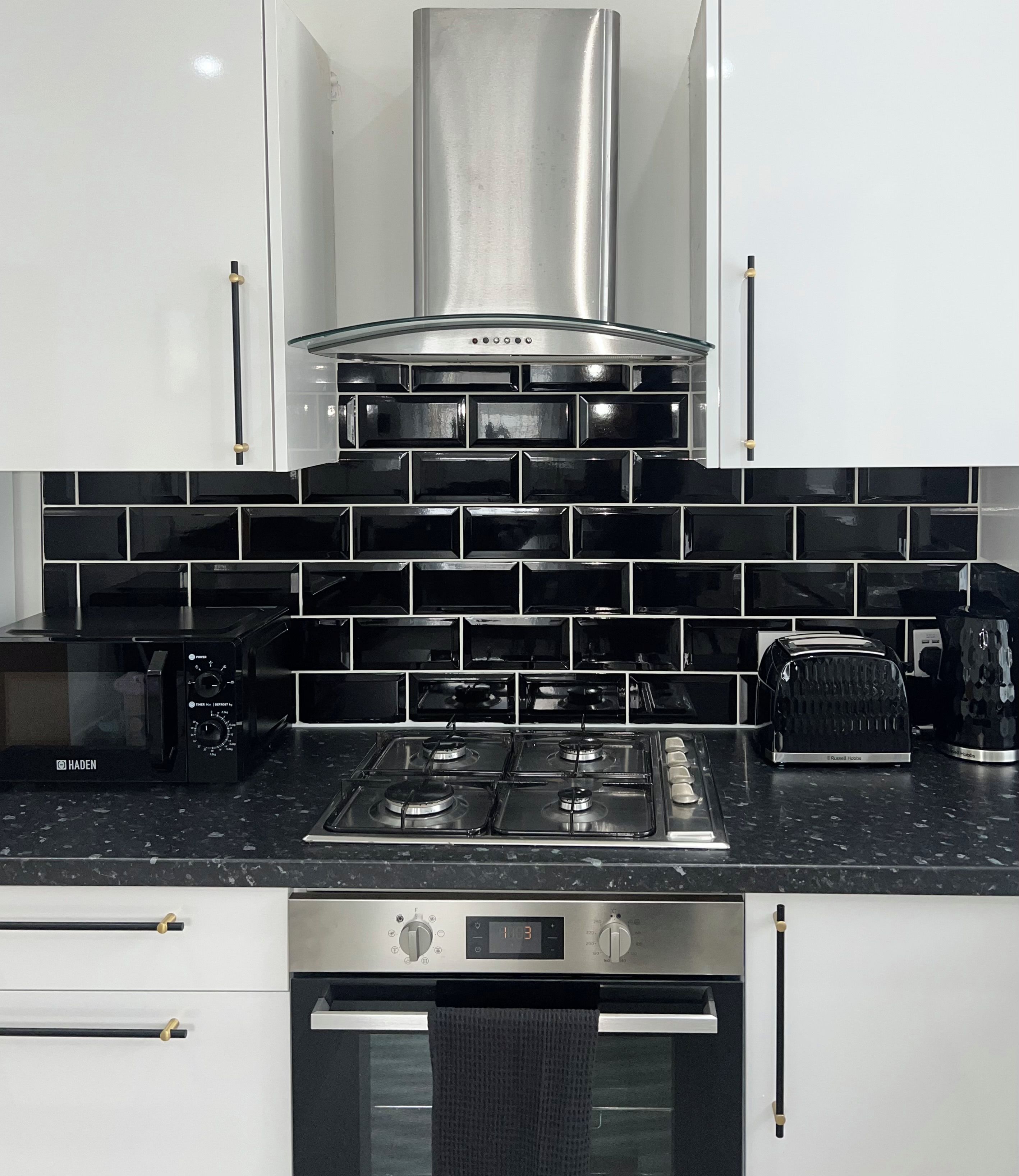 Une cuisine moderne équipée d’une cuisinière à gaz, d’un four et d’une hotte en acier inoxydable.