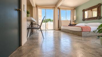 Ein Hotelzimmer mit einem Bett, einem Schreibtisch, einem Sessel und einem großen Fenster.