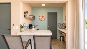 A compact kitchen with a central island, chairs, and a door leading to another room.