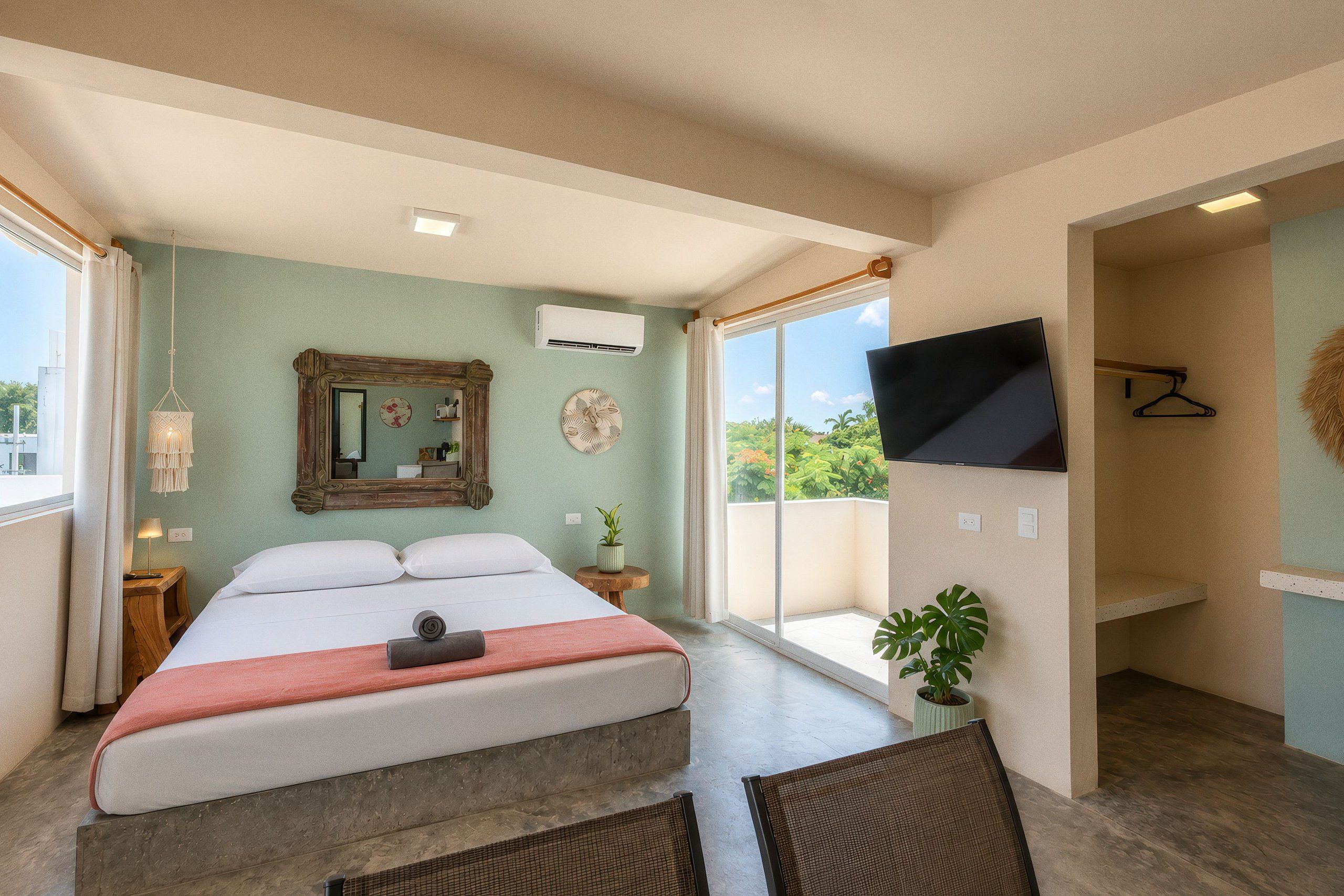 A bedroom with a bed, a TV, a window, and a balcony.