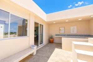 Un patio exterior moderno con un banco integrado, una planta en maceta y vistas al cielo.