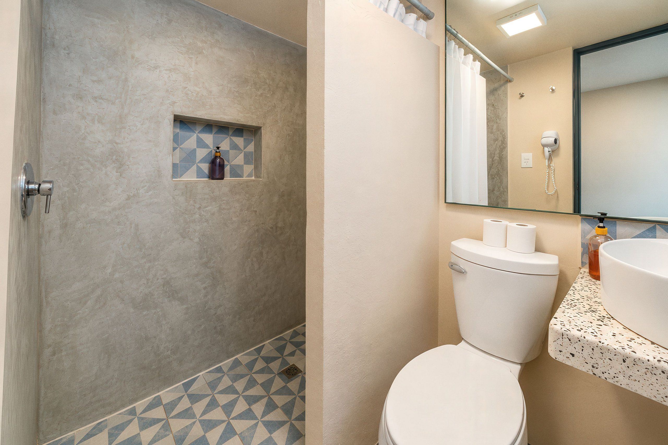 Un baño con inodoro, lavamanos, ducha y espejo.