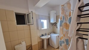 Ein Badezimmer mit Toilette, Waschbecken, Waschmaschine und Duschvorhang.