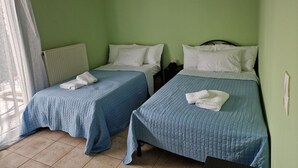 Ein Zimmer mit zwei Betten, jeweils mit blauer gesteppter Bettdecke und weißen Kissen, einem Heizkörper und einer Klimaanlage an der Wand.